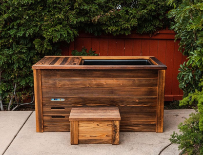 Wooden cold plunge with a smaller matching bench on a patio.